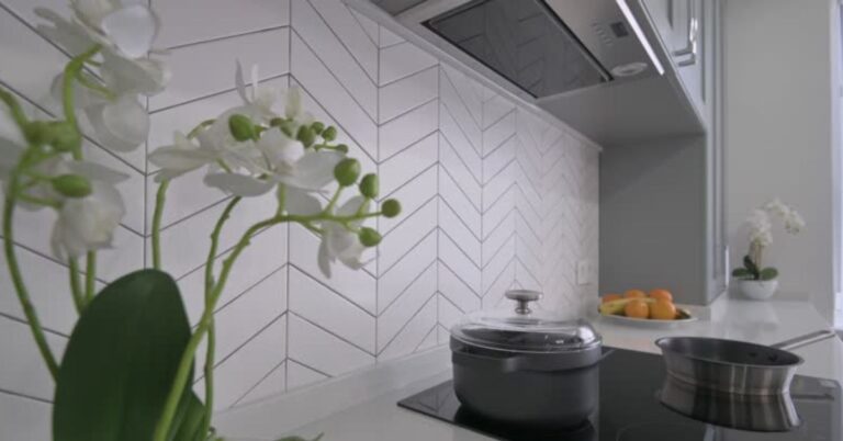 Close-up of warm neutral handmade current ceramic tiles and kitchen tiles organized in a herringbone kitchen splashback.